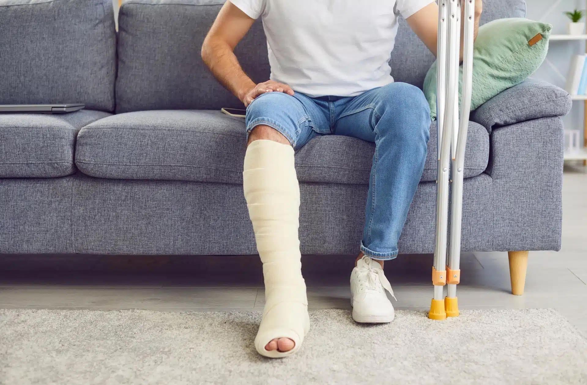 Person sitting on a couch with a leg cast, illustrating a serious injury that could be worsened in a car accident.