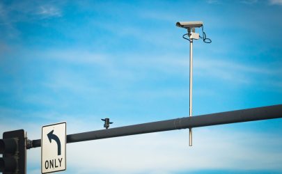 Red light traffic camera mounted above a Phoenix, Arizona intersection monitoring vehicles for traffic violations