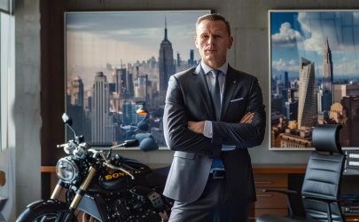 a powerful motorcycle accident lawyer stands confidently in a sleek, modern office adorned with city skyline artwork, exuding authority and determination as they prepare to advocate for their clients.